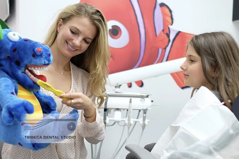 Dentist showing child how to brush teeth with a puppet in NYC clinic.